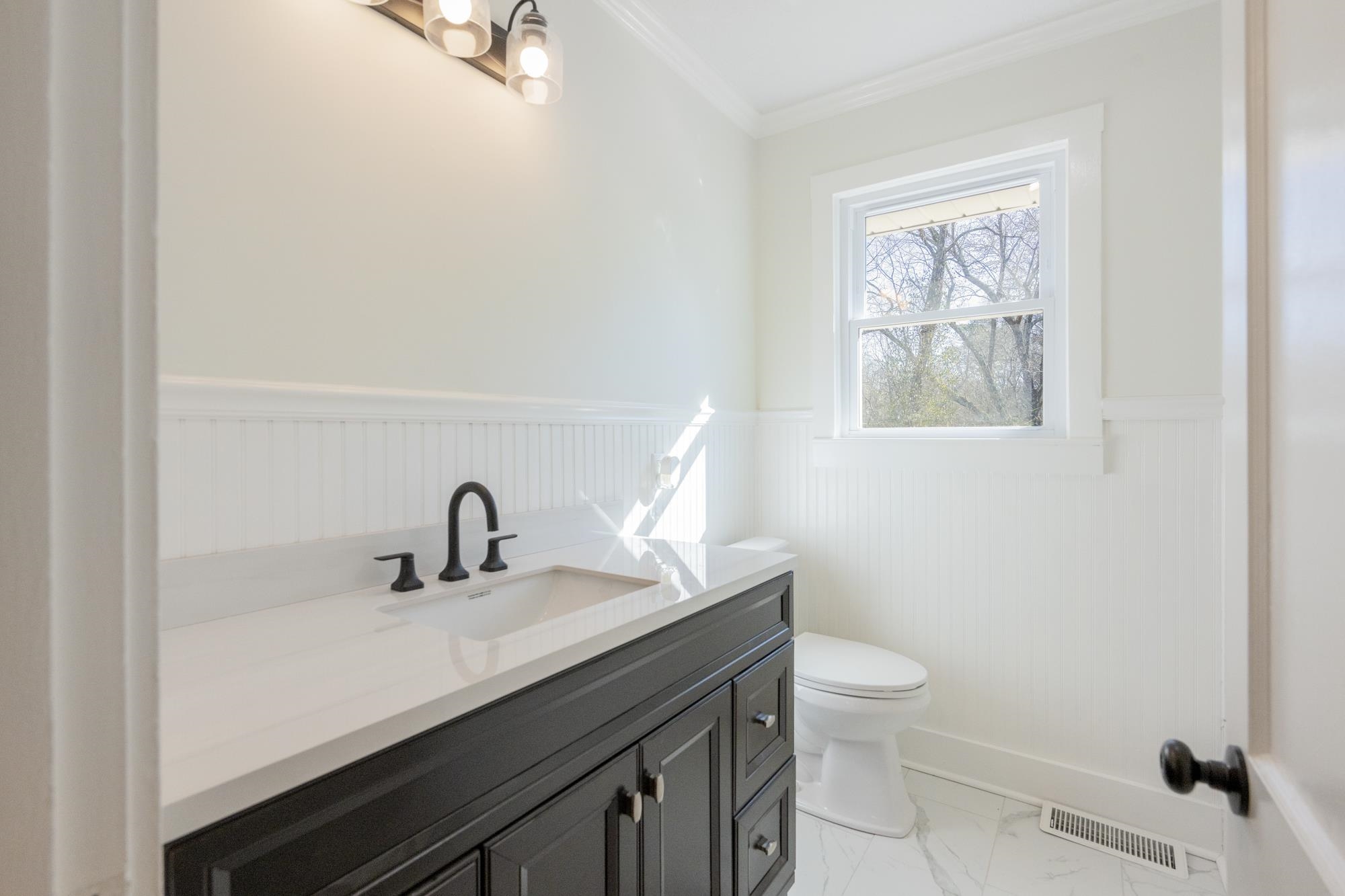 242 Broad Street North Lexington, TN 38351 - Photo 9 of 40 Half bath with wainscoting, vanity, light marble finish floors, and crown molding