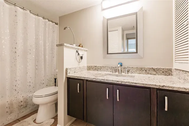 a bathroom with a granite countertop sink toilet and mirror