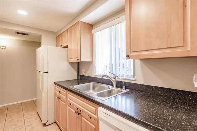 a kitchen with stainless steel appliances granite countertop a sink and a refrigerator
