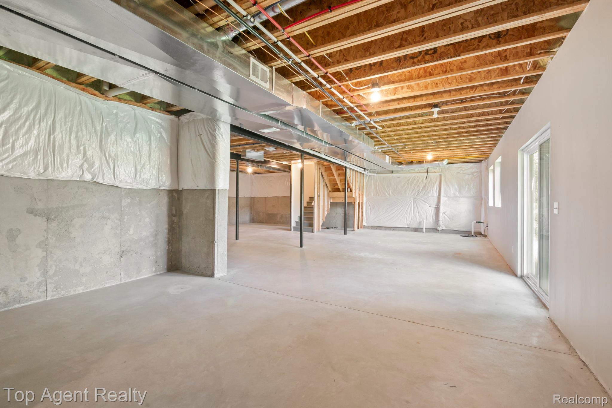 63770 Dequindre Road Washington, MI 48095 - Photo 47 of 61 Unfinished lower level featuring exposed ceiling joists, concrete flooring, concrete foundation walls, and a sliding glass door