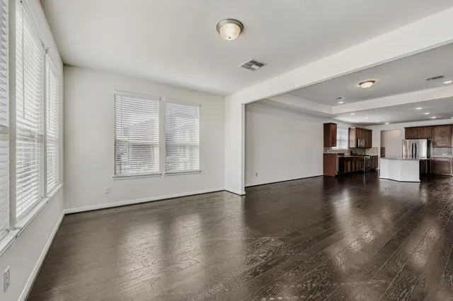 a view of empty room with wooden floor and a window