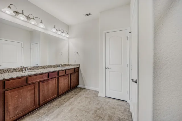 a spacious bathroom with a granite countertop sink and a mirror