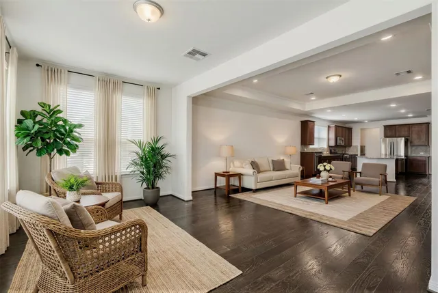 a living room with furniture and potted plants with wooden floor
