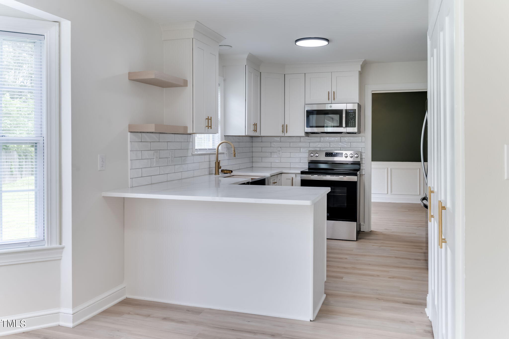 3912 Kildaire Farm Road Apex, NC 27539 - Photo 12 of 37 a kitchen with stainless steel appliances a refrigerator a sink a stove a microwave and wooden floor