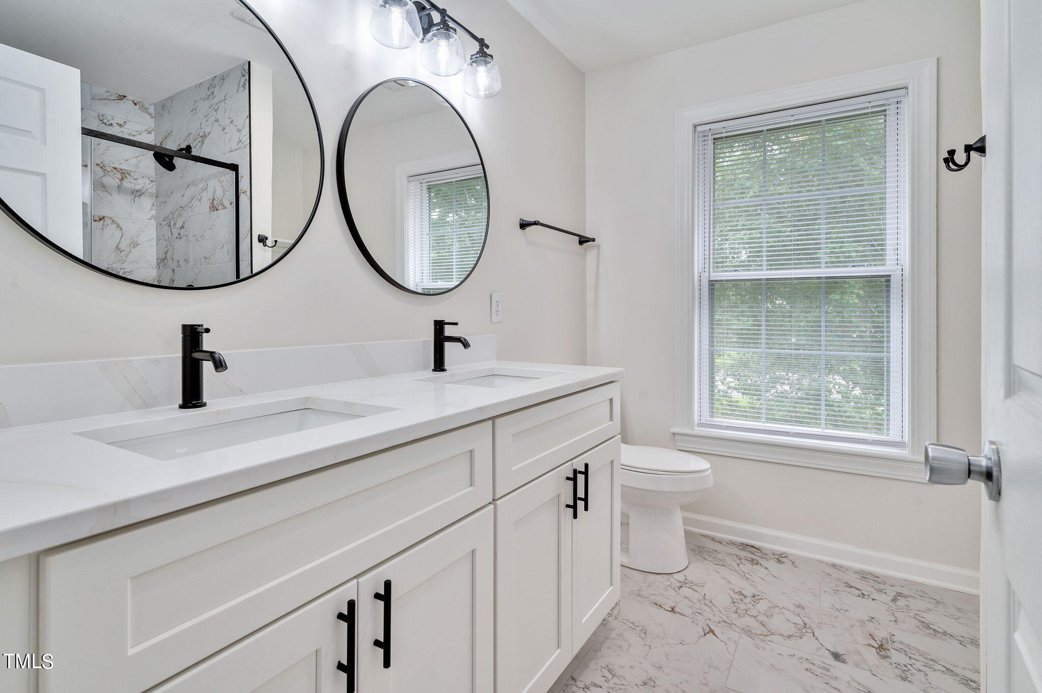3912 Kildaire Farm Road Apex, NC 27539 - Photo 24 of 37 a bathroom with a double vanity sink a toilet and a mirror