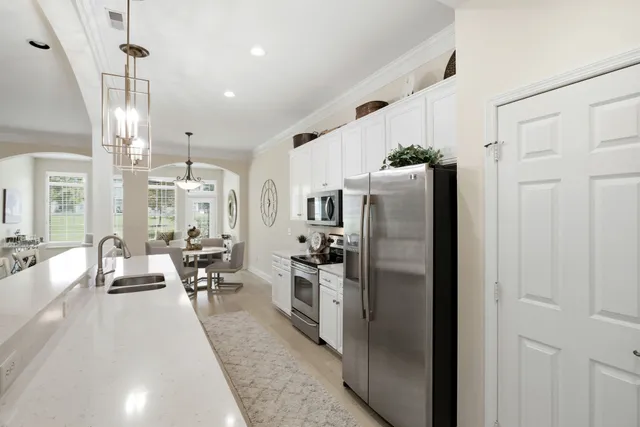 a kitchen with stainless steel appliances a refrigerator a stove a sink dishwasher a dining table and chairs with wooden floor