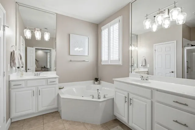 a bathroom with a bathtub a double vanity sink and a mirror