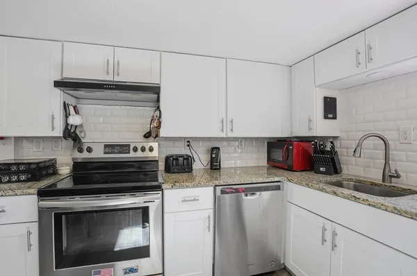 a kitchen with granite countertop a stove sink and cabinets