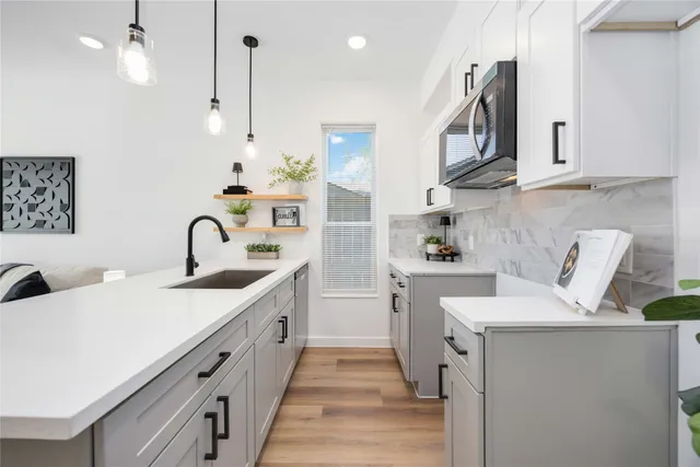 a kitchen with white cabinets and sink