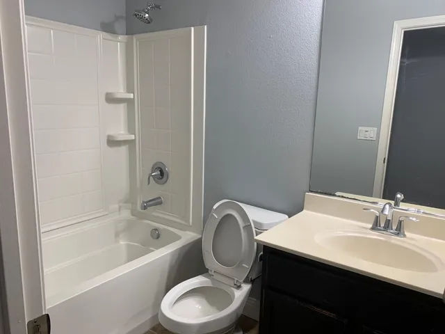 a bathroom with a granite countertop sink toilet a mirror and bathtub
