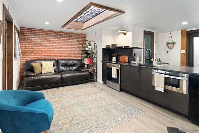 a kitchen with stainless steel appliances granite countertop a table chairs in it and wooden floors