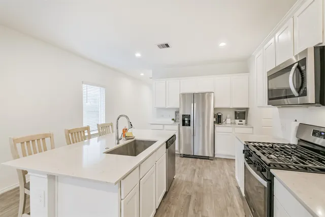 a kitchen with stainless steel appliances granite countertop a sink stove and refrigerator