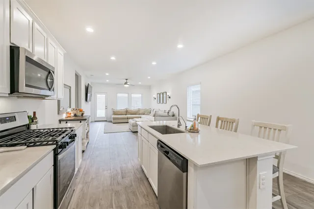 a kitchen with a sink a counter top space stainless steel appliances and cabinets