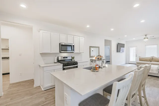 a kitchen with white cabinets a sink stove and refrigerator