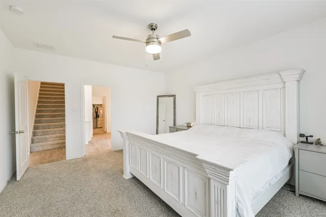 a bedroom with a bed a ceiling fan and a dresser