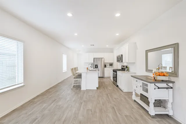a large white kitchen with stainless steel appliances granite countertop a lot of counter space and wooden floor