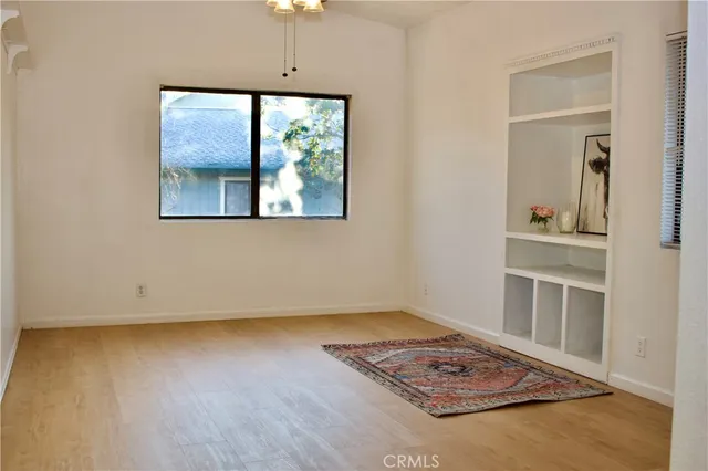 an empty room with wooden floor closet and windows