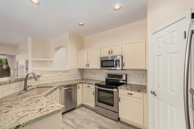 a kitchen with stainless steel appliances granite countertop a sink stove oven and refrigerator