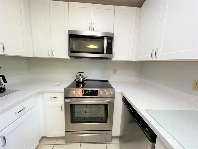 a kitchen with stainless steel appliances granite countertop white cabinets a stove top oven and a sink