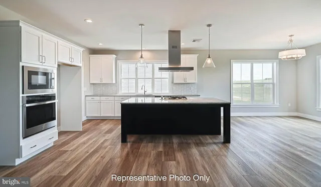 a living room with stainless steel appliances kitchen island granite countertop wooden floor sink and cabinets