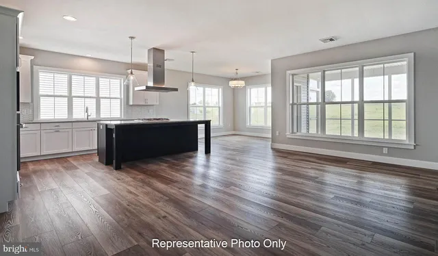 a large kitchen with kitchen island wooden floors and stainless steel appliances