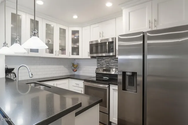 a kitchen with stainless steel appliances granite countertop a sink a stove and a refrigerator