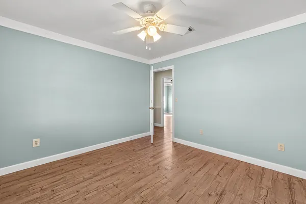 a view of an empty room with window and wooden floor