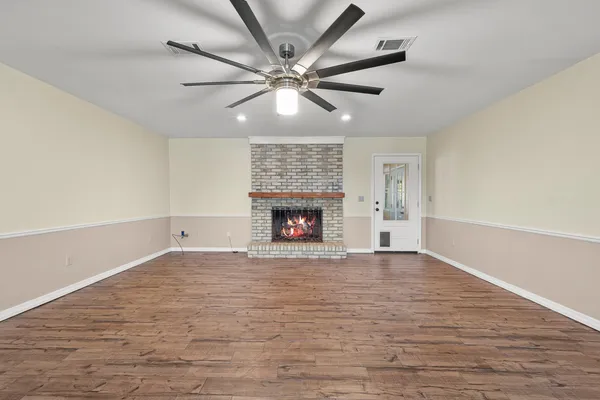 a view of a livingroom with wooden floor a ceiling fan and kitchen space