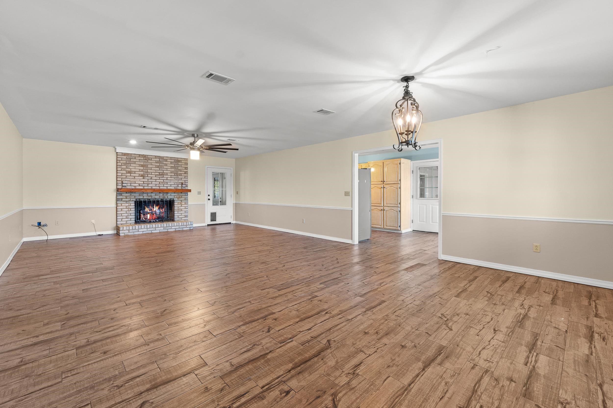 49 Cr 178 Road Iuka, MS 38852 - Photo 7 of 32 an empty room with wooden floor fireplace and chandelier fans