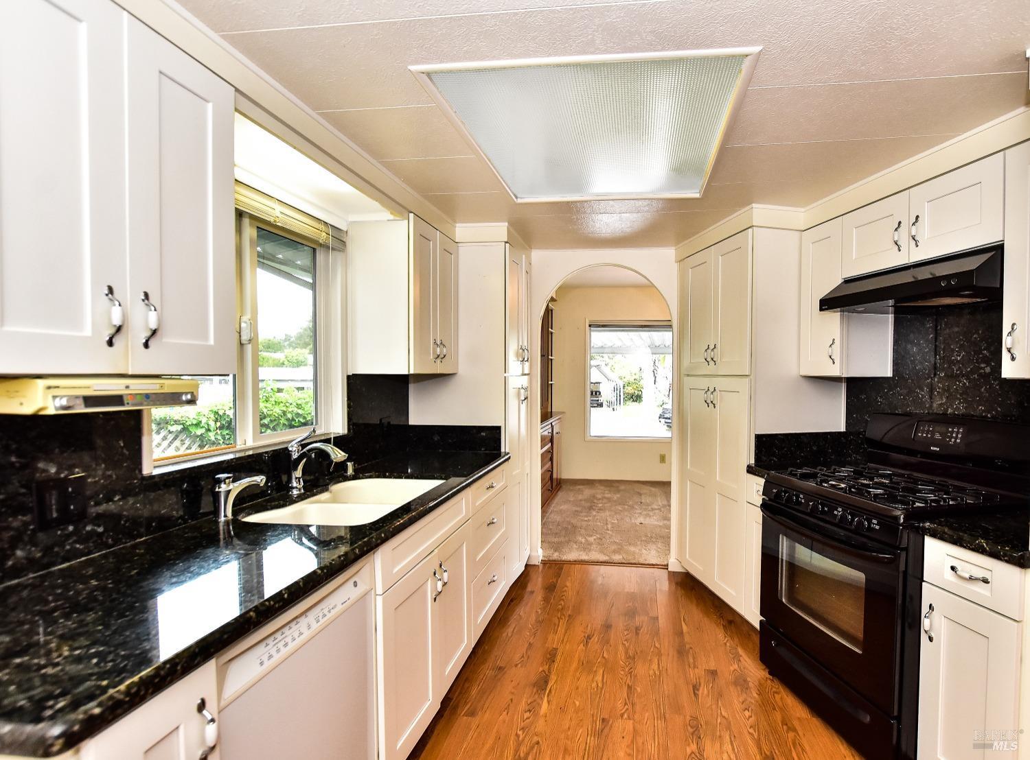 a kitchen with granite countertop stainless steel appliances a sink a stove cabinets counter space and a window