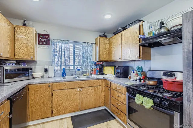 a kitchen with stainless steel appliances granite countertop a sink a stove and a wooden cabinets