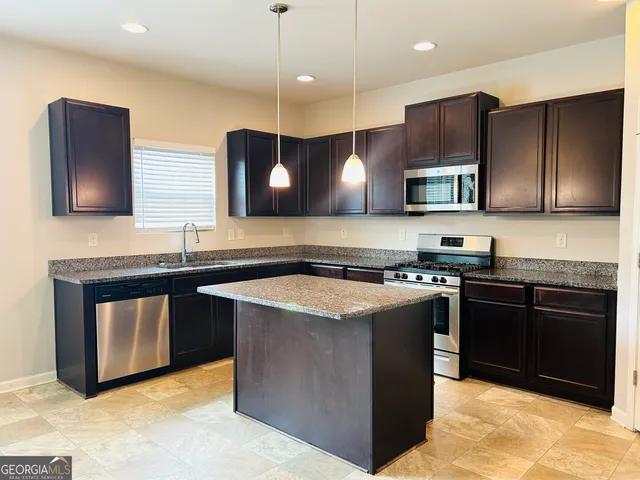 a kitchen with stainless steel appliances granite countertop a stove a sink and a microwave