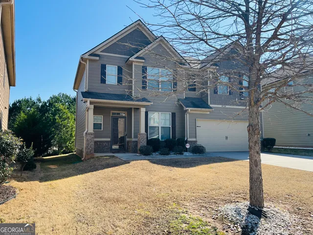 a front view of a house with a yard outdoor seating and covered with trees