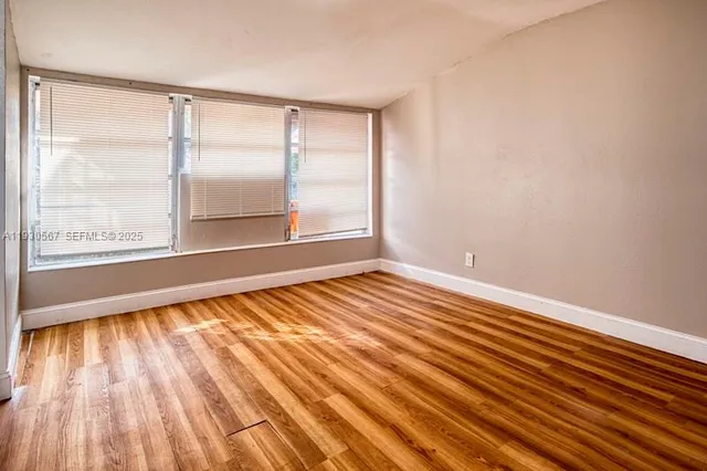 a view of an empty room and wooden floor and windows