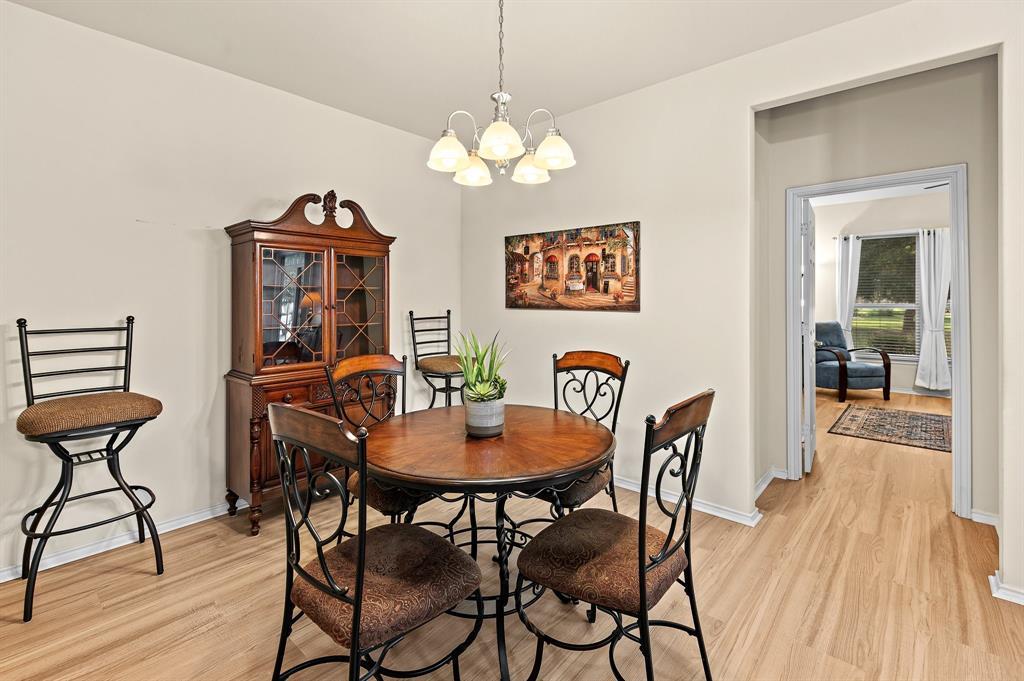 109 Providence Street Georgetown, TX 78633 - Photo 13 of 31 Dining area featuring wood-finish flooring, a contemporary chandelier, and a framed doorway opening to an additional room