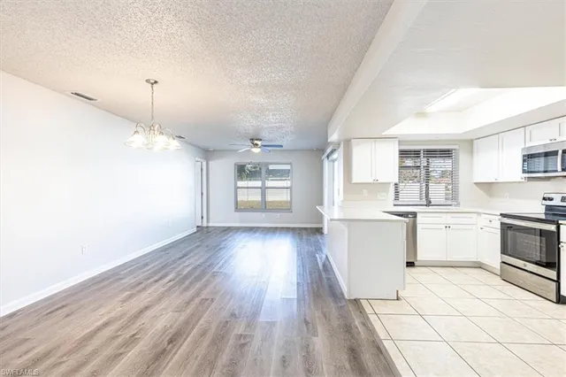 a kitchen with granite countertop a stove a sink and white cabinets with wooden floor