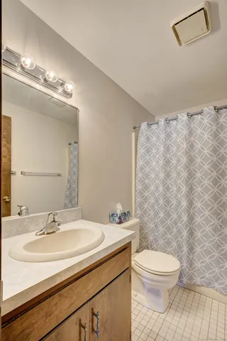 a bathroom with a sink a toilet a mirror and shower curtain