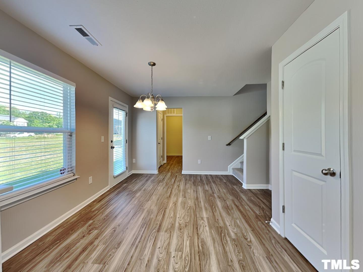 1908 Buffalo Way Durham, NC 27704 - Photo 4 of 18 a view of a room with wooden floor staircase and a kitchen space