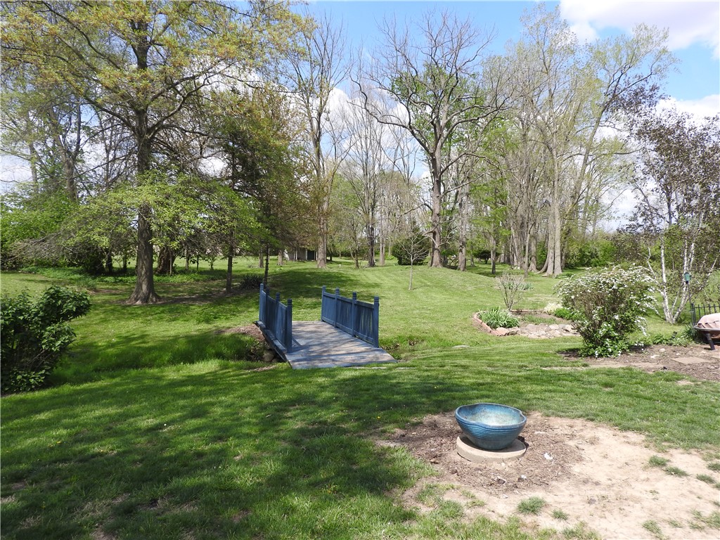 2185 East Loy Road Piqua, OH 45356 - Photo 17 of 19 This expansive yard features lush greenery and a charming bridge over a tranquil stream.
