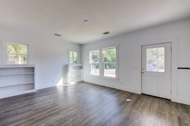 an empty room with wooden floor and windows