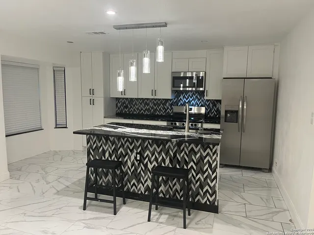 a kitchen with stainless steel appliances granite countertop a sink and a refrigerator