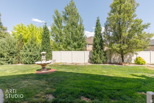 2327 Bluff Ridge Drive Syracuse, UT 84075 - Photo 48 of 66 Expansive lawn area featuring a decorative garden fountain on a paver base, surrounded by mature trees and evergreen shrubs
