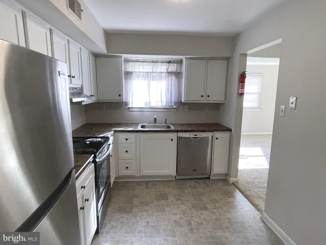 a kitchen with granite countertop a refrigerator stove and sink