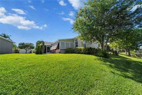 a view of a house next to a big yard and large trees