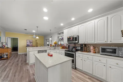 a kitchen with a sink dishwasher stove and white cabinets with wooden floor