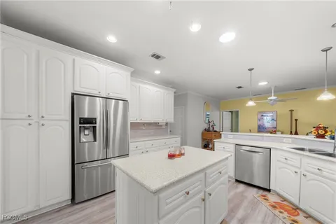 a kitchen with a sink a refrigerator and white cabinets