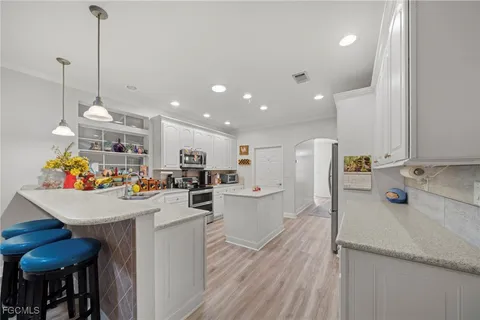 a view of a kitchen with kitchen island stainless steel appliances sink stove microwave and cabinets