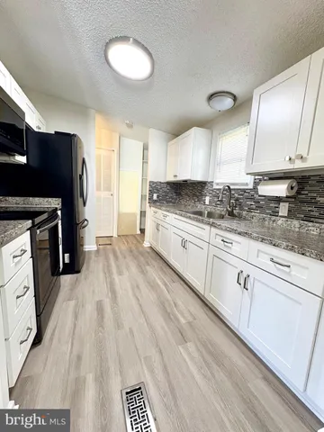 a kitchen with granite countertop a stove a sink dishwasher and a refrigerator with wooden floor