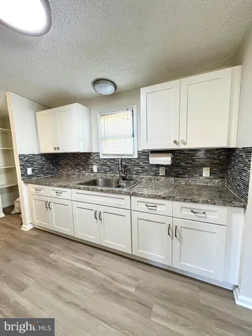 a kitchen with granite countertop a sink cabinets and wooden floor
