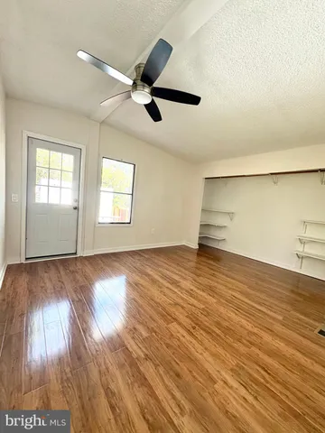 a view of empty room with wooden floor and fan